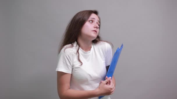 Очаровательная молодая женщина делает нормальный жест, сохраняя синюю папку . — стоковое видео