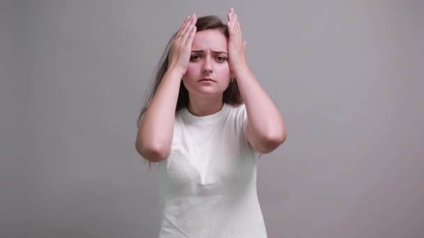 Втомилася жінка в моді біла сорочка тримає руки на голові, має головний біль — стокове відео