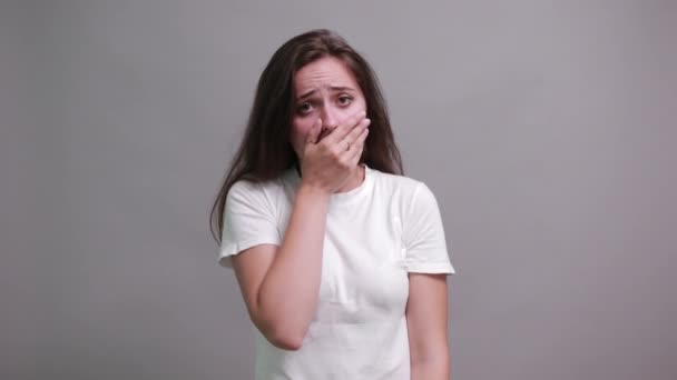 Mujer joven infeliz cubierto la boca con las manos, mirando decepcionado — Vídeo de stock