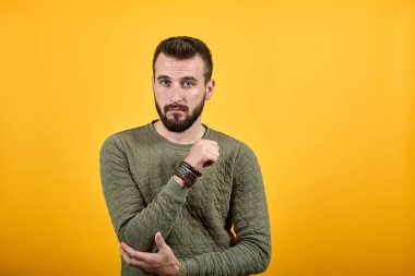 Neşeli bir adam kameraya bakıyor, dirseğini günlük kıyafetlerle tutuyor.