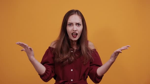 Disappointed young woman in maroon dress spreads hands, looking unhappy — 비디오