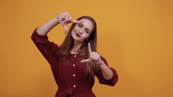 Alegre dama en vestido granate mirando directamente, haciendo gesto de victoria, sonriendo — Vídeo de stock