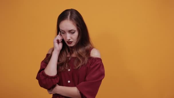 Brunette tired woman in maroon dress keeping hand on head, having headache — ストック動画