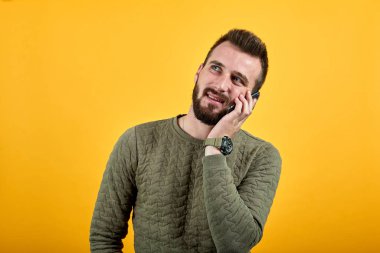 Yakışıklı, beyaz bir adam. Elini yanağından ayırmıyor, yukarı bakıyor.