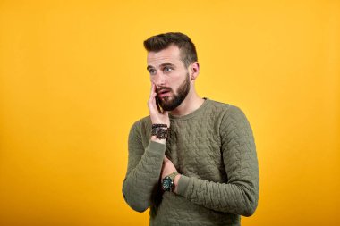 Şok olmuş yakışıklı adam kameraya bakıyor, ağzını ellerle kapatıyor.