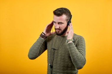 Kulaklık takan, ellerini üstünde tutan, kapalı gözlerle müziğin tadını çıkaran bir adam.