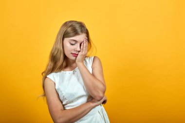 Yorgun sarışın genç kadın ellerini yüzüne koyuyor, uyku jesti yapıyor.