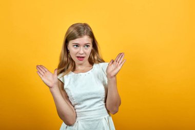 Çekici, sarışın genç bir kadın ellerini açıyor, kafası karışık görünüyor.