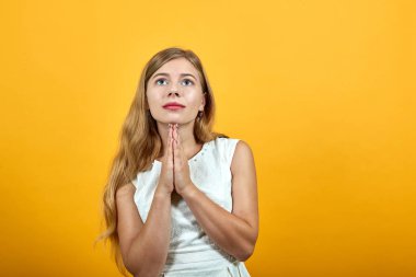 Barışçıl sarışın genç kadın el ele tutuşuyor. Dua ediyor, yukarı bakıyor.