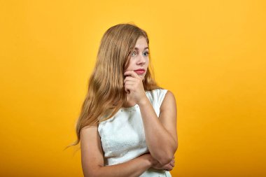 Çekici bir kadın çenesini kapatıyor, yan bakıyor, konuyu düşünüyor.