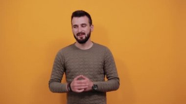 İzole edilmiş turuncu arka planda neşeli bir adam. Başparmak havada, gülümsüyor.