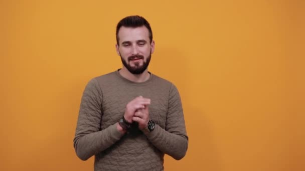 Fiatal fehér férfi a kamerába néz, összetartja a kezét, mosolyog — Stock videók
