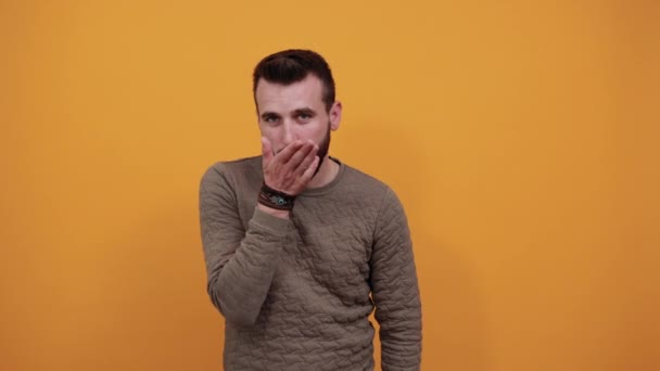 Красивий чоловік над ізольованим помаранчевим тлом дме, відправляє повітряний поцілунок — стокове відео