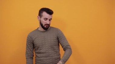 İzole edilmiş turuncu arka planda yakışıklı bir adam, elindeki saate bakıyor.