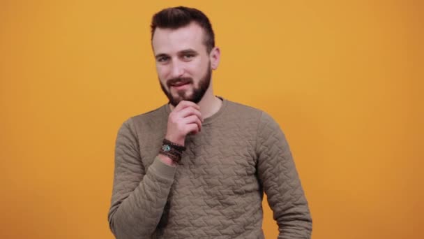 Jonge vrolijke man houdt de hand op kin, denken aan iets — Stockvideo