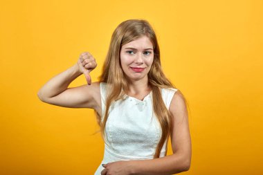 Genç ve çekici bir kadın başparmağını eğip, hayal kırıklığına uğramış görünüyor.