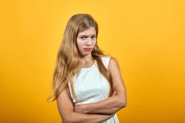 Hayal kırıklığına uğramış genç bir kadın ellerini çapraz tutuyor, yanaklarını şişiriyor.