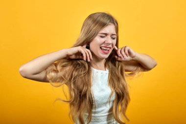 Tatminsiz kadın parmaklarını kulaklarında tutuyor, gözleri kapalı bakıyor.