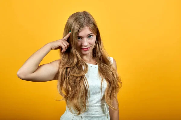 Encantadora mujer joven caucásica manteniendo el dedo en la cabeza, mostrando buen corte de pelo —  Fotos de Stock