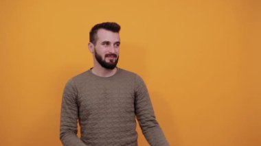 Yakışıklı, beyaz bir genç adam bir tarafa işaret ediyor, gülümsüyor.