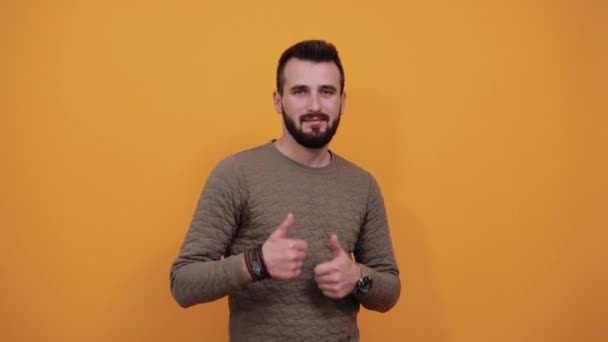 Alegre homem bonito sem barba olhando para a câmera, mantendo os polegares para cima — Vídeo de Stock