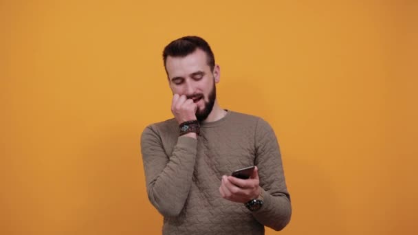 Homem bonito com os olhos fechados, mantendo a mão no queixo, segurando o telefone — Vídeo de Stock