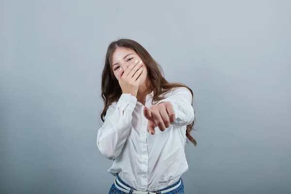 Happy young woman covering mouth with hand, pointing finger at camera — Stock Photo, Image