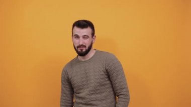 Moda yeşili kazak giyen yakışıklı beyaz adam kameraya bakıyor, göz kırpıyor.