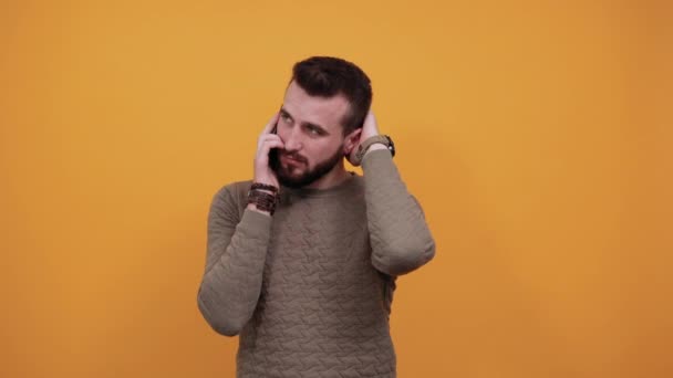 Snygg kaukasisk ung man hålla hand på huvudet, talar i telefon — Stockvideo