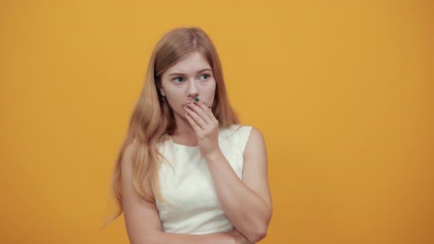 Ελκυστική γυναίκα που καλύπτει το στόμα με το χέρι, κρατώντας το χέρι στο κεφάλι φαίνεται φοβισμένη — Αρχείο Βίντεο