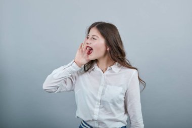 Şok olmuş bir kadın, ağzı açık bir şekilde el ele tutuşuyor, yan bakıyor.