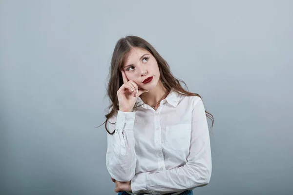 Jolie jeune femme gardant la main sur la tête, pensant à quelque chose — Photo