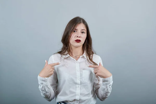 Blank vrolijke brunette vrouw wijzend vingers naar zichzelf, op zoek ongelukkig. — Stockfoto