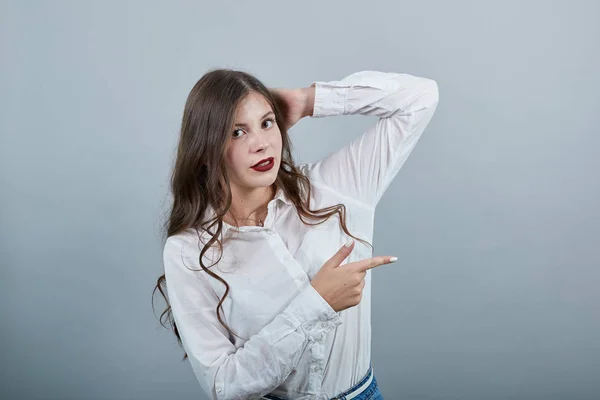 Atractieve vrouw houdt hand op hoofd, wijzend vinger opzij, kijkend naar een camera — Stockfoto