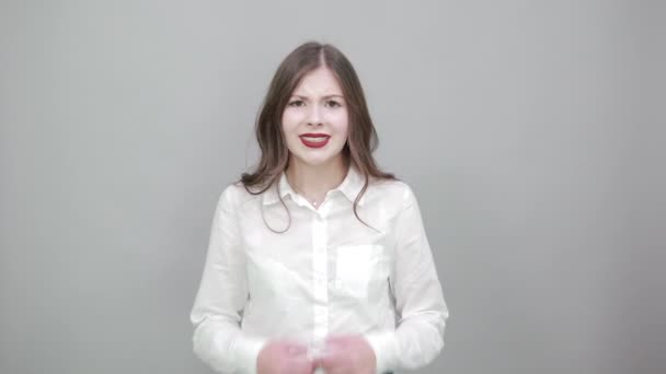 Charmante junge Frau im modischen weißen Hemd breitet Hände aus und blickt in die Kamera — Stockvideo