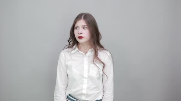 ファッションの白いシャツの失望した若い女性は、混乱しているように見える — ストック動画