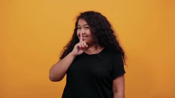 Mujer afro-americana feliz manteniendo el dedo en la boca, haciendo gesto shh — Vídeo de stock