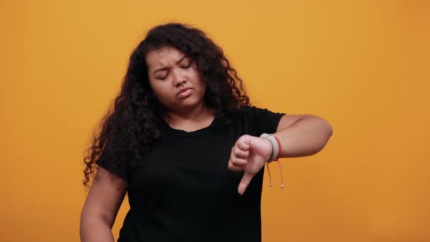 親指を上下に指す失望巻きアフロ系アメリカ人の若い女性. — ストック動画