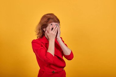 Kafkasyalı yorgun genç bir kadın. Elle yüzünü kapatıyor. Moda kırmızısı ceket giyiyor.