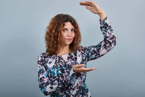 Charmante kaukasische junge Frau, die Raum zwischen den Händen zeigt und direkt hinsieht — Stockfoto