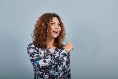 Neşeli Kafkasyalı genç kadın yumruk atıyor, gülümsüyor, mutlu görünüyor.