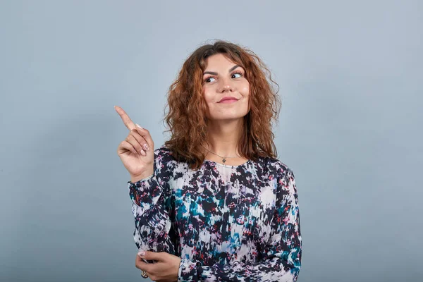 Привлекательная кавказская молодая женщина, указывающая пальцем вверх, улыбающаяся — стоковое фото