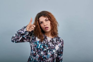 Çekici beyaz kadın kamerayı işaret ediyor, kafası karışık.