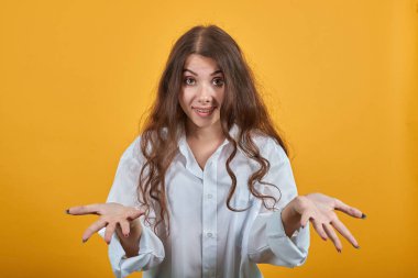 Gülümseyen beyaz gömlekli beyaz kadın ellerini açıyor, şaşırmış görünüyor.
