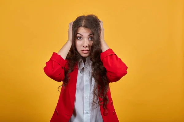 Schockierte brünette junge Frau hält die Hände auf dem Kopf, hat Kopfschmerzen, ist verwirrt — Stockfoto