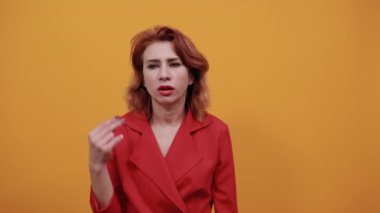Hayal kırıklığına uğramış beyaz kadın parmaklarını birarada tutuyor, kameraya bakıyor.