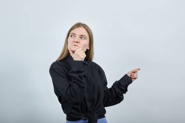 Odaklanmış bir kadın çenesini tutarak, parmağını bir tarafa kaldırarak, sorunu düşünüyor.