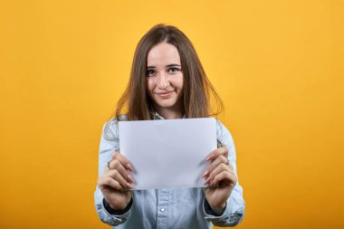 Neşeli çekici kadın beyaz kağıt tutuyor, gülümsüyor, kameraya bakıyor..
