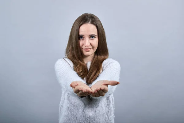 Calm woman wearing sweater showing space on palms, looking at camera — 스톡 사진