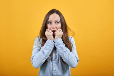 Tırnak yiyen, yumruklarını ağzında tutan korkmuş beyaz kadın..